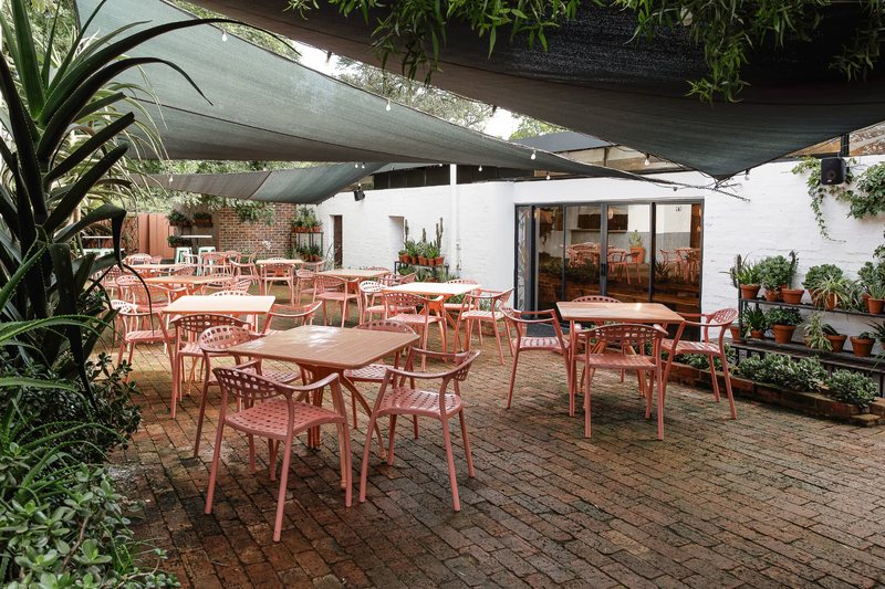 The brick courtyard outside Bloot with terracotta tables and chairs under shade sails and festoon lights