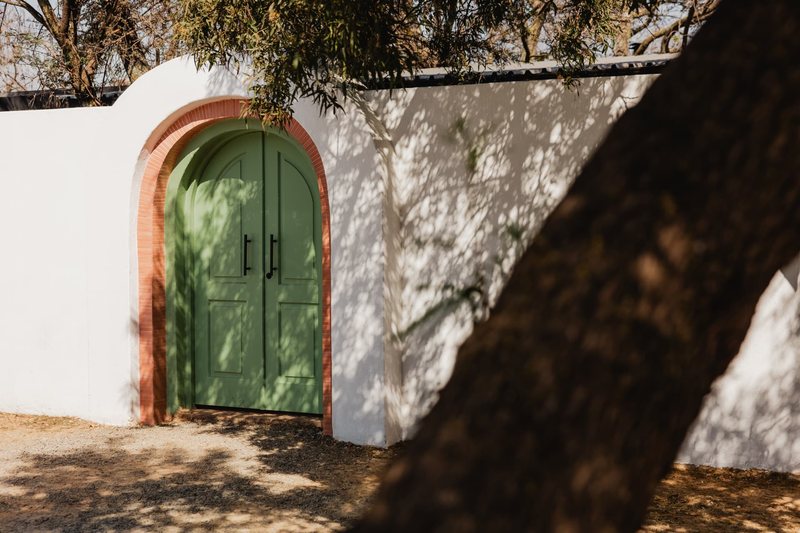 The arched sage-green double doors set in a whitewashed wall at the entrance to Still