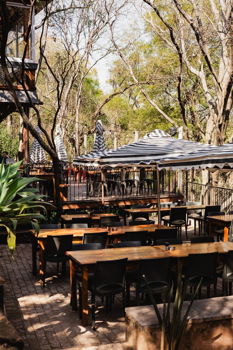 Long timber tables on the Bunker Terrace beneath striped umbrellas, with the raised wooden deck behind