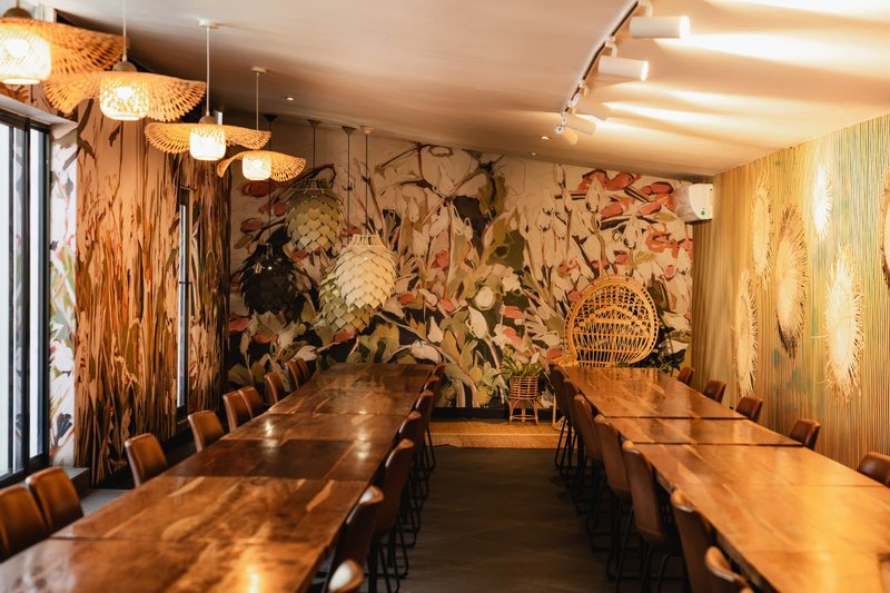 Bloot's painted botanical mural and rattan peacock chair at the end of two long banquet tables