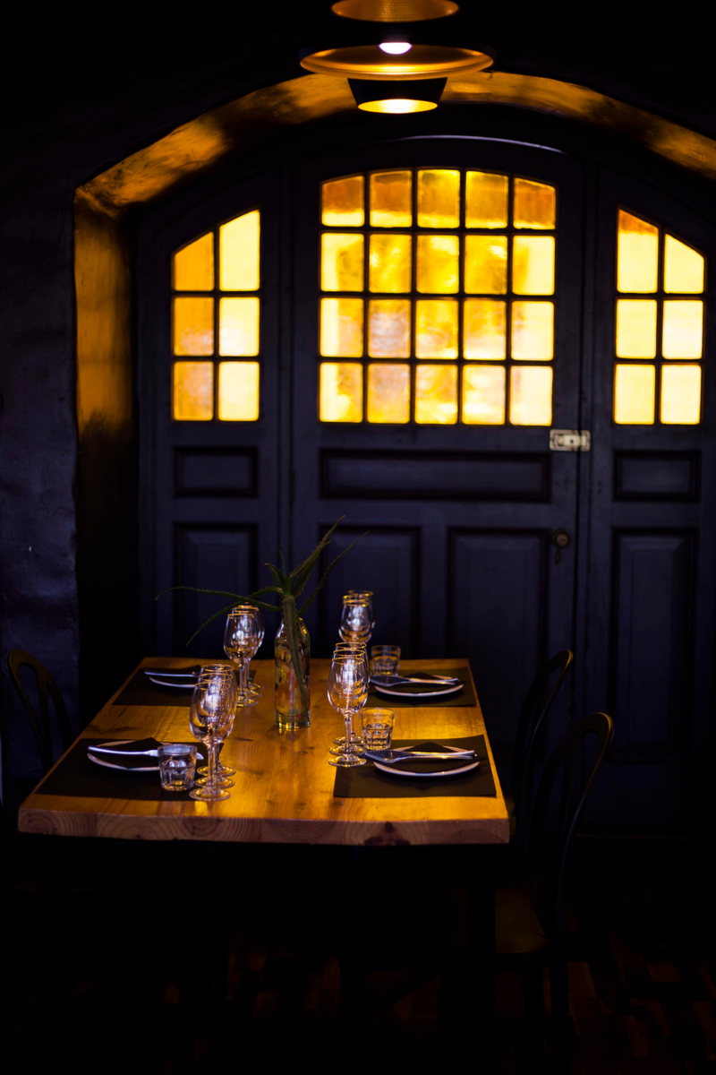 A table set with glassware and black napkins in front of the Main Function Room's warmly lit arched double doors
