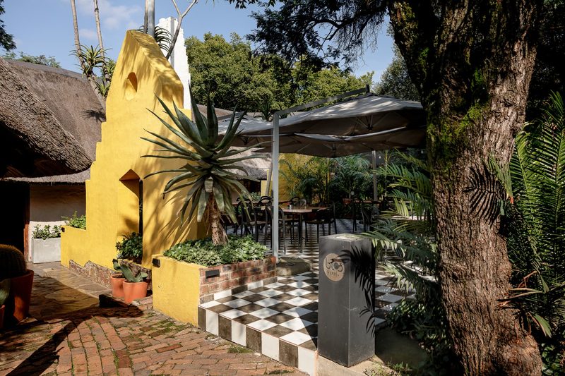 Entrance to the Courtyard past the yellow gable wall and aloe, with seating beyond