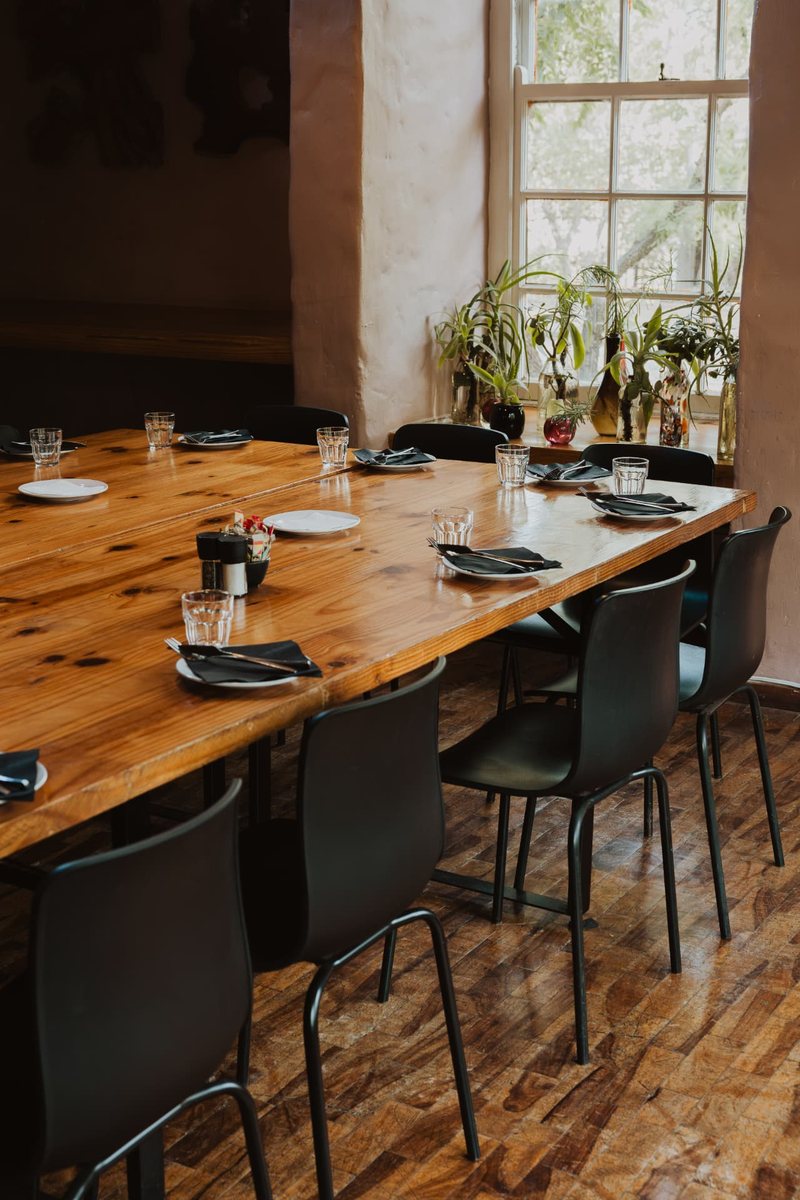 Close view of the Oak Room table laid with plates, glassware and dark napkins beside the window plants