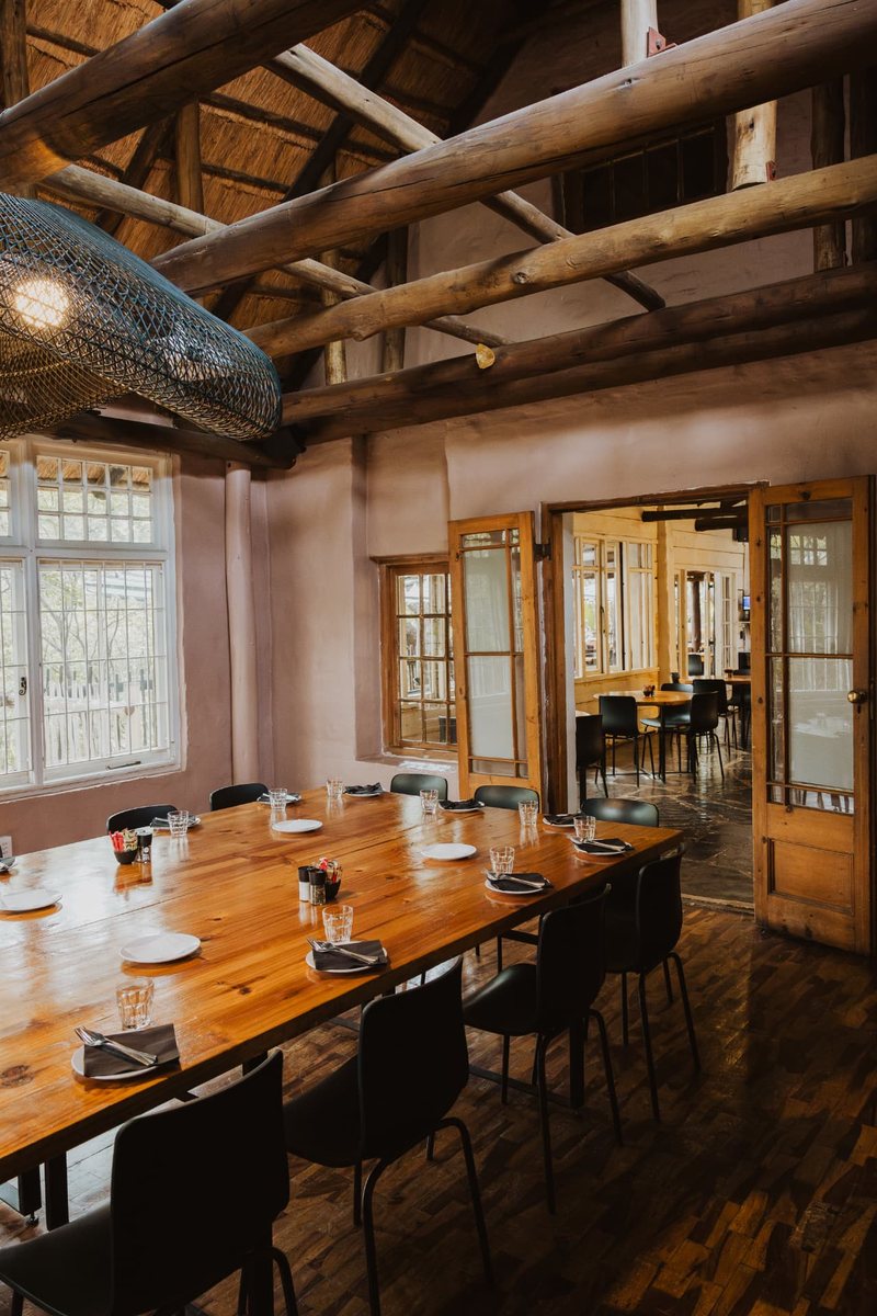 Oak Room table set for a meal under the timber trusses and thatched roof, with doors open to the café
